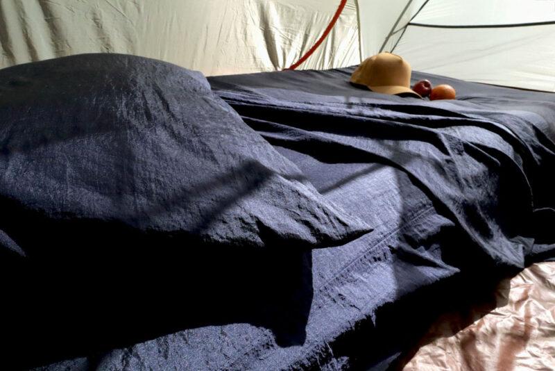 dingotex eco-friendly travel sheet in deep ocean blue colour inside tent unmade bed kids stuff on it